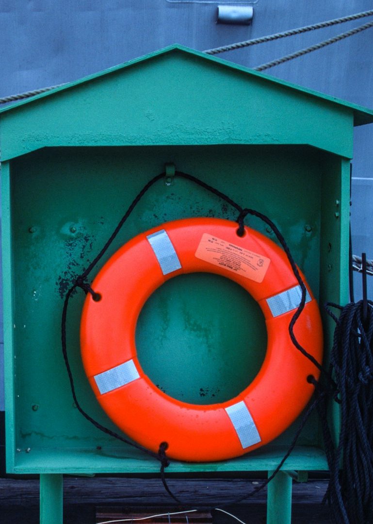 Orangener Rettungsring in einem grünen Holzhaus.